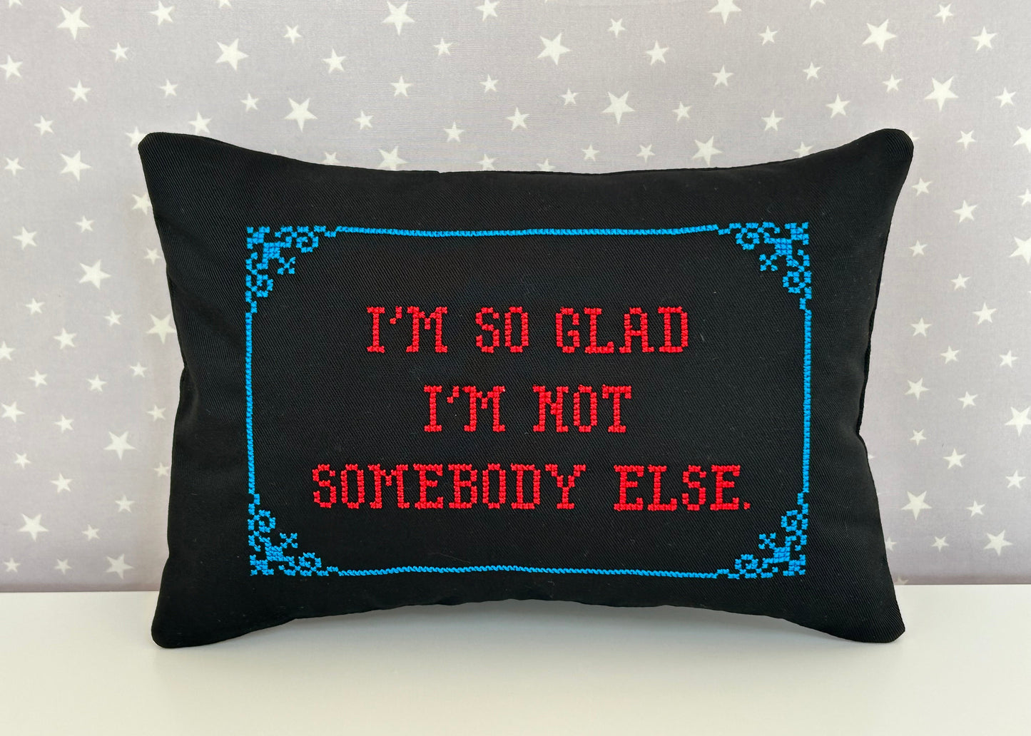 Black pillow with red and blue text on a star-patterned background