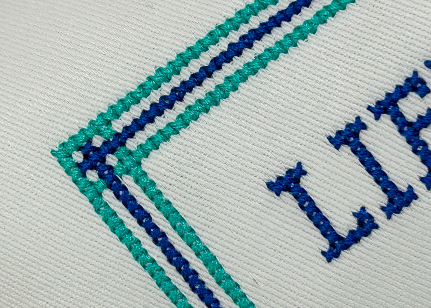 Close-up of embroidered text and lines on a fabric surface