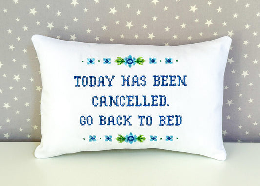 Decorative pillow with cross-stitched text on a star-patterned background