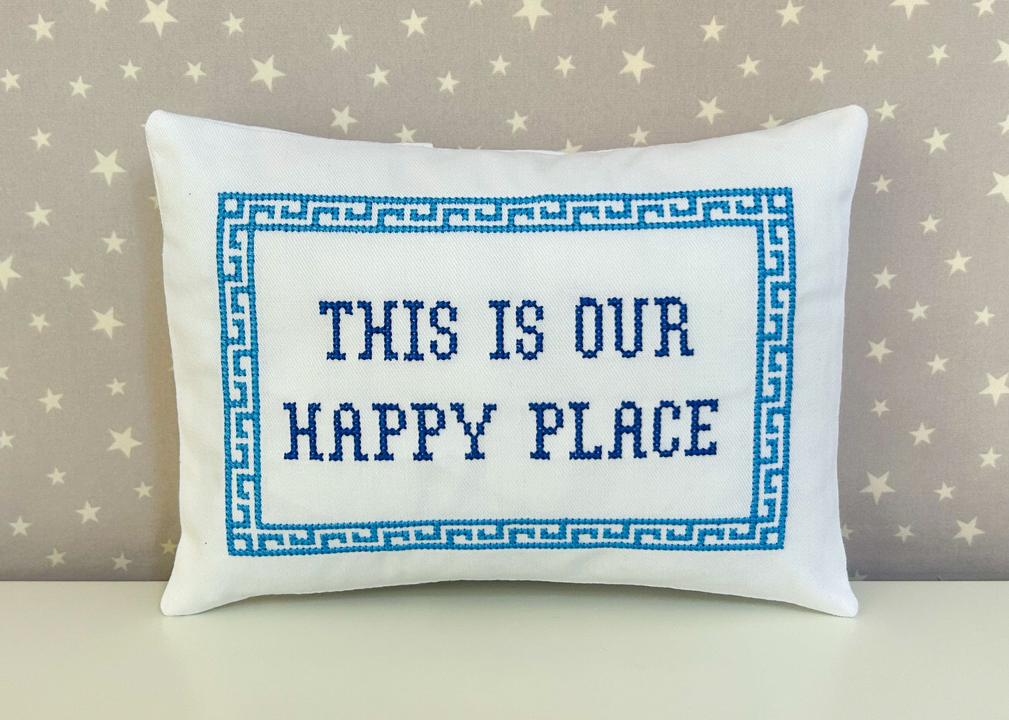 Decorative pillow with 'This is our happy place' text on a star-patterned background