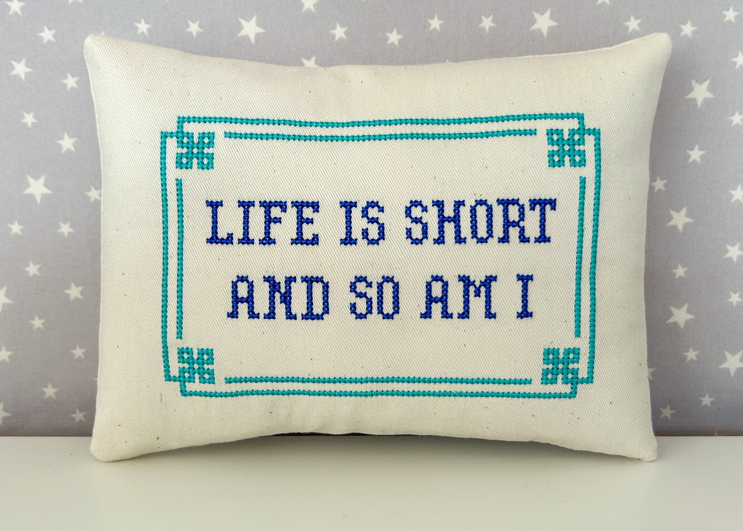 Decorative pillow with 'Life is short and so am I' text on a star-patterned background