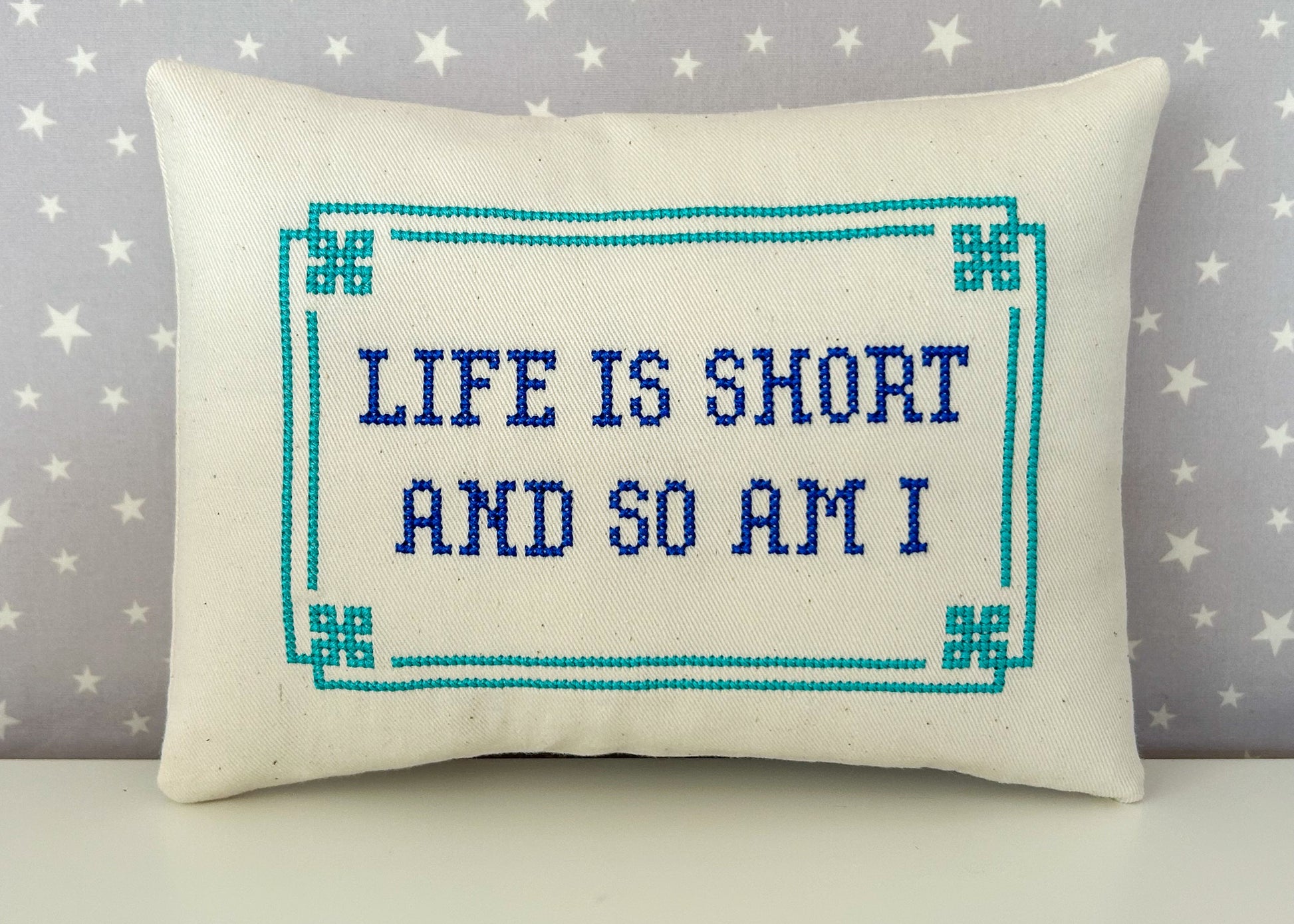 Decorative pillow with 'Life is short and so am I' text on a star-patterned background