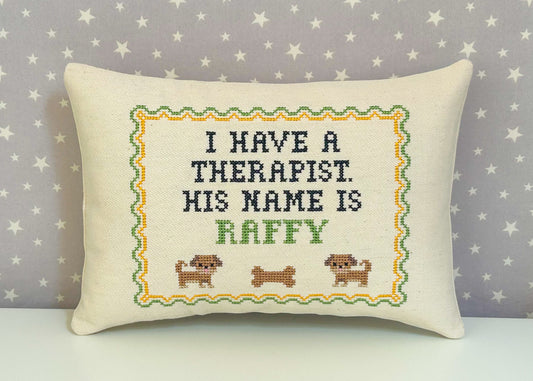 Decorative pillow with cross-stitched text and dog illustrations on a star-patterned background