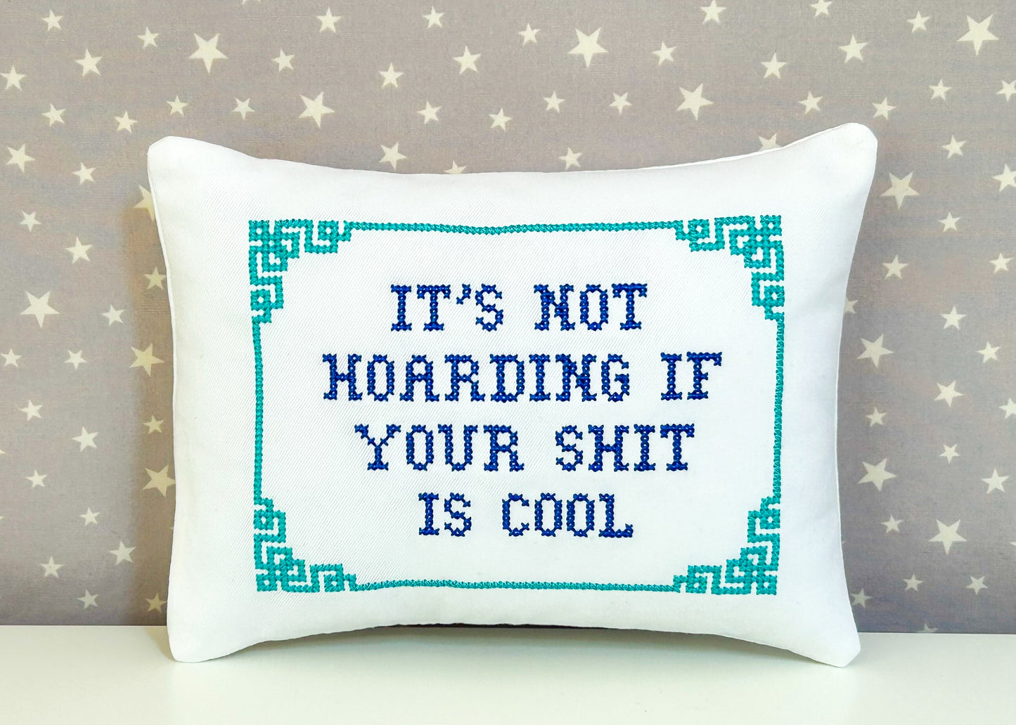Decorative pillow with cross-stitched text on a star-patterned background