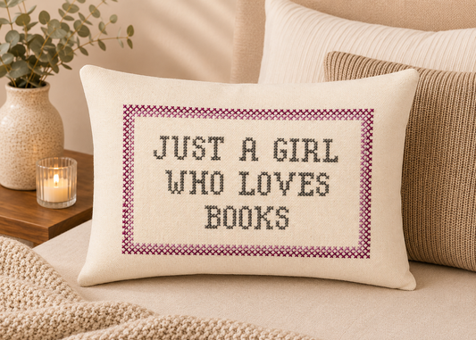 Decorative pillow with 'Just a Girl Who Loves Books' text on a bed.
