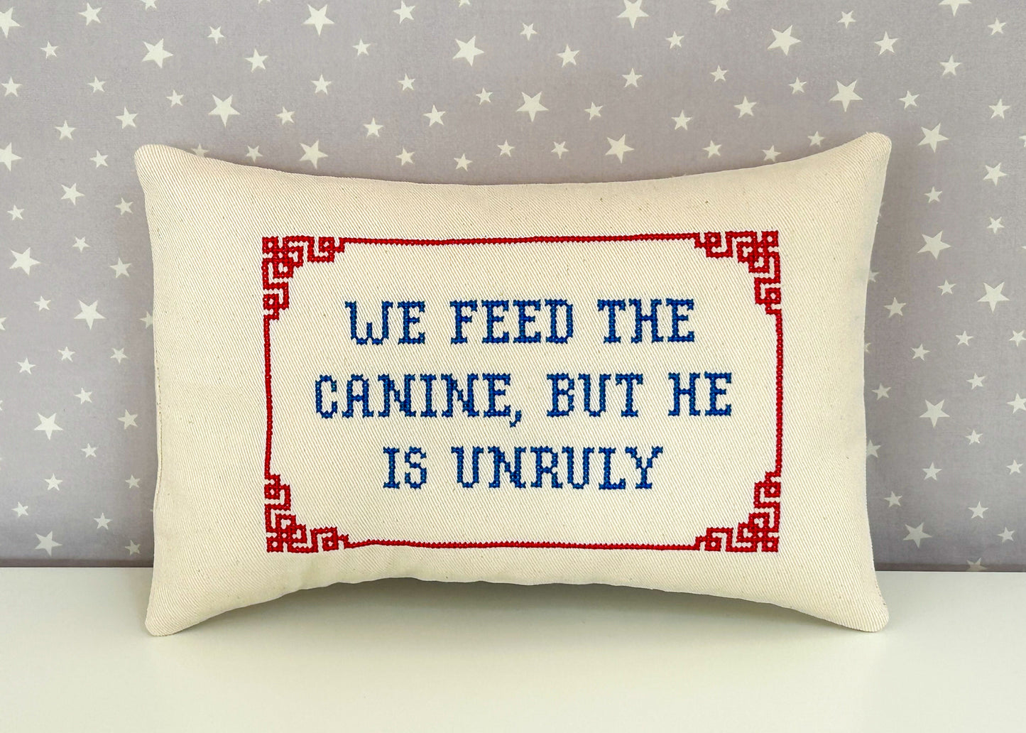 Decorative pillow with embroidered text against a star-patterned background