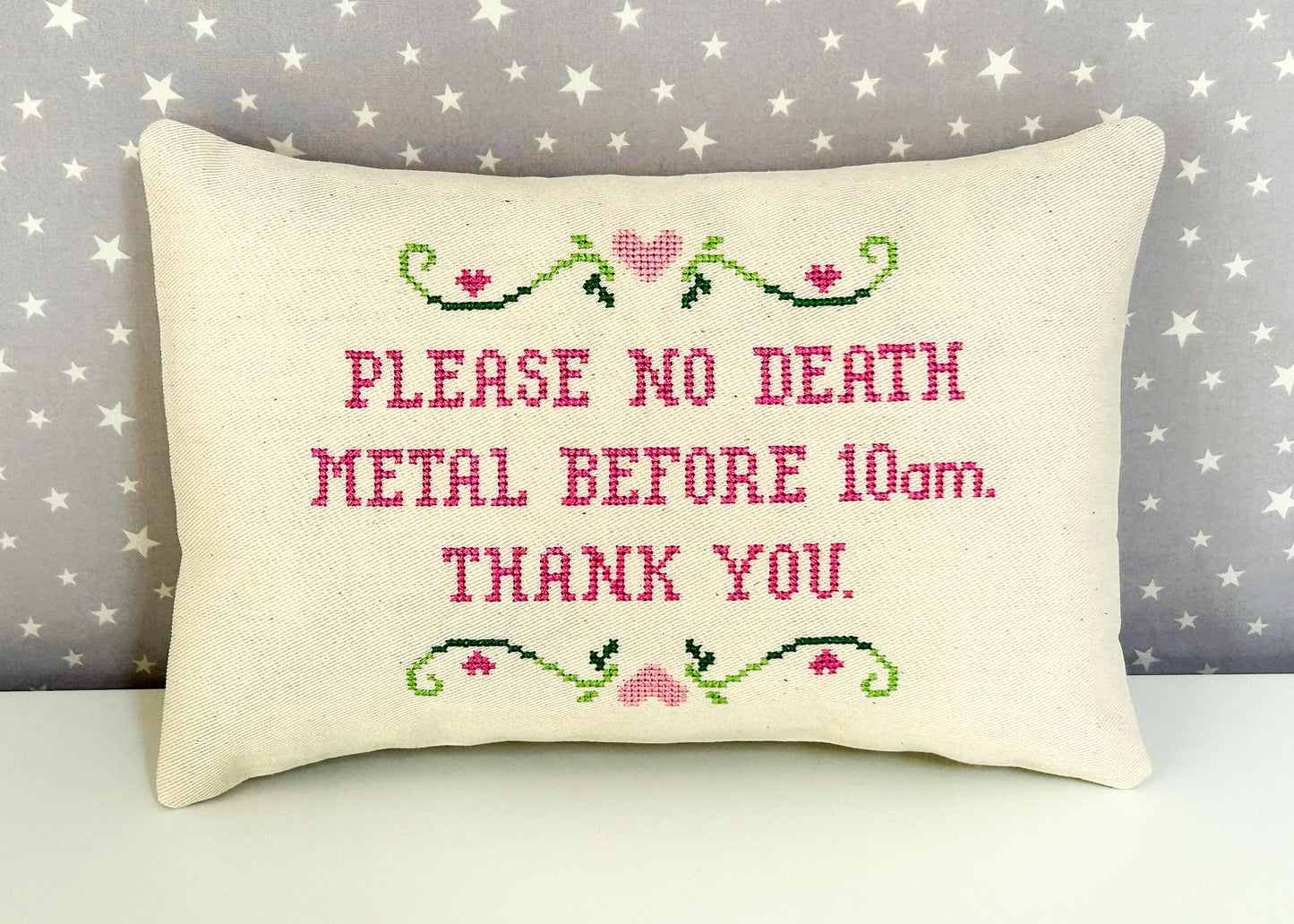Decorative pillow with cross-stitched text on a star-patterned background