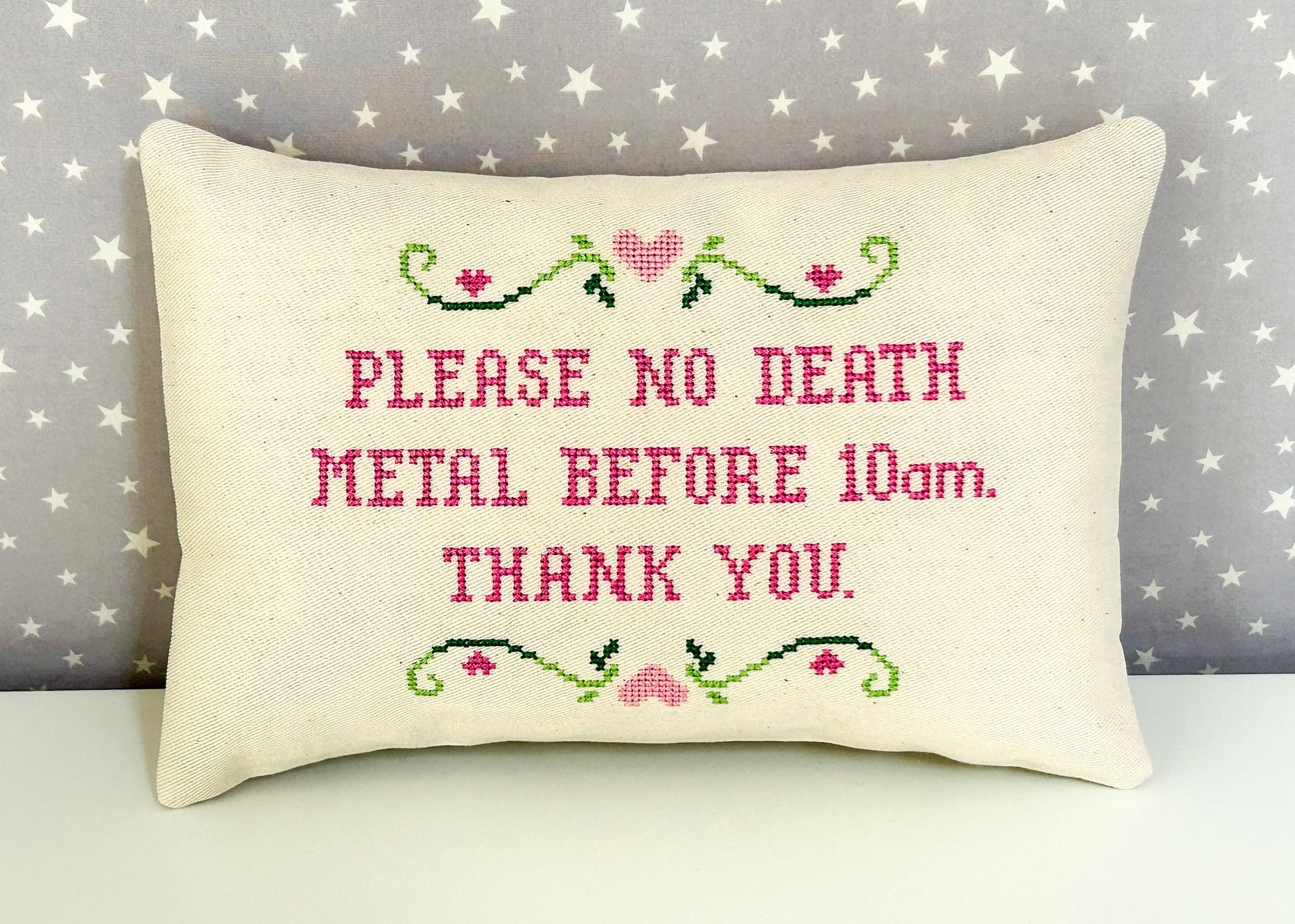 Decorative pillow with cross-stitched text on a star-patterned background