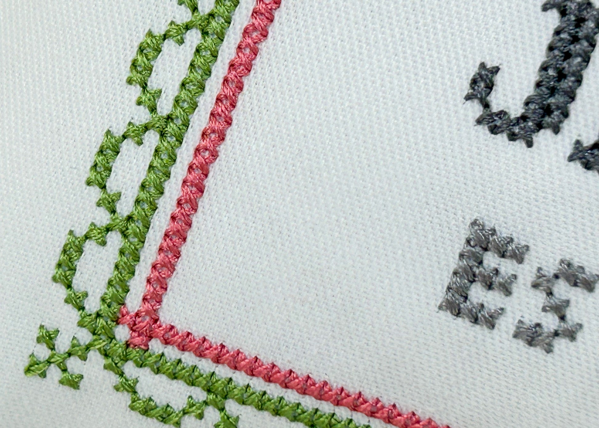 Embroidered fabric with green and red lace trim on a white background