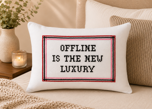 Decorative pillow with 'Offline is the New Luxury' text on a bed.