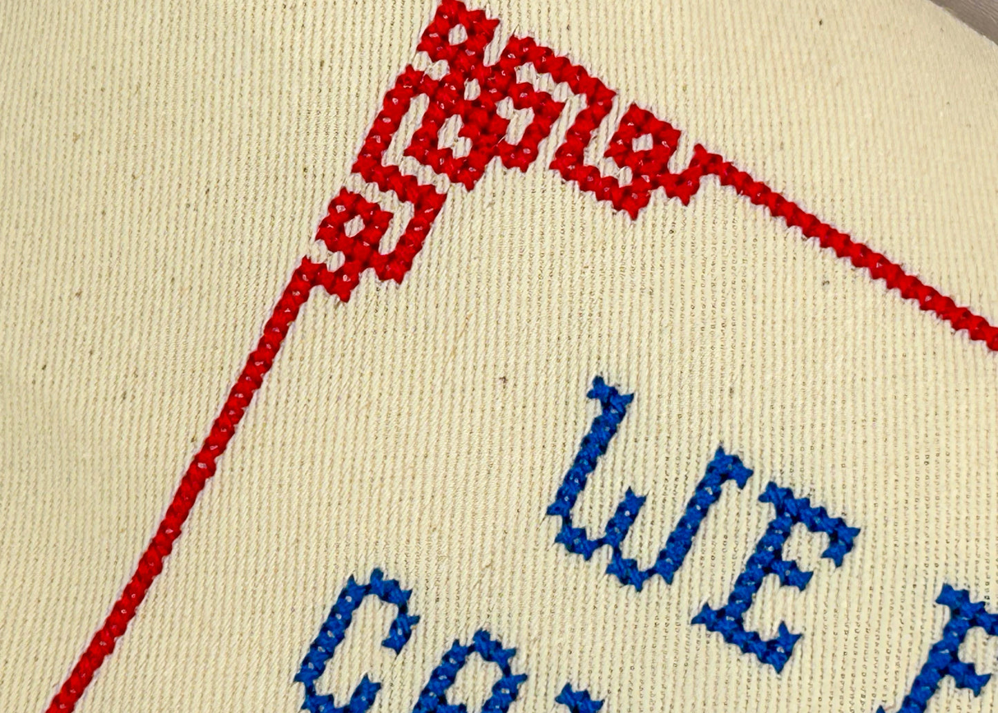 Embroidered text on a fabric with red and blue thread