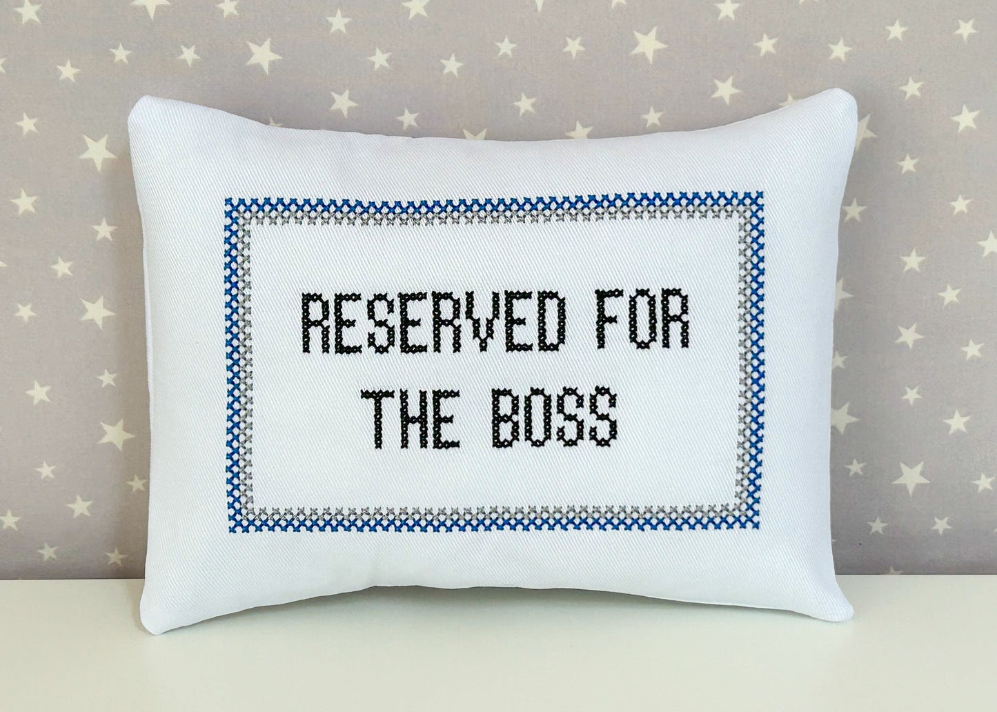 White pillow with 'Reserved for the Boss' text on a star-patterned background