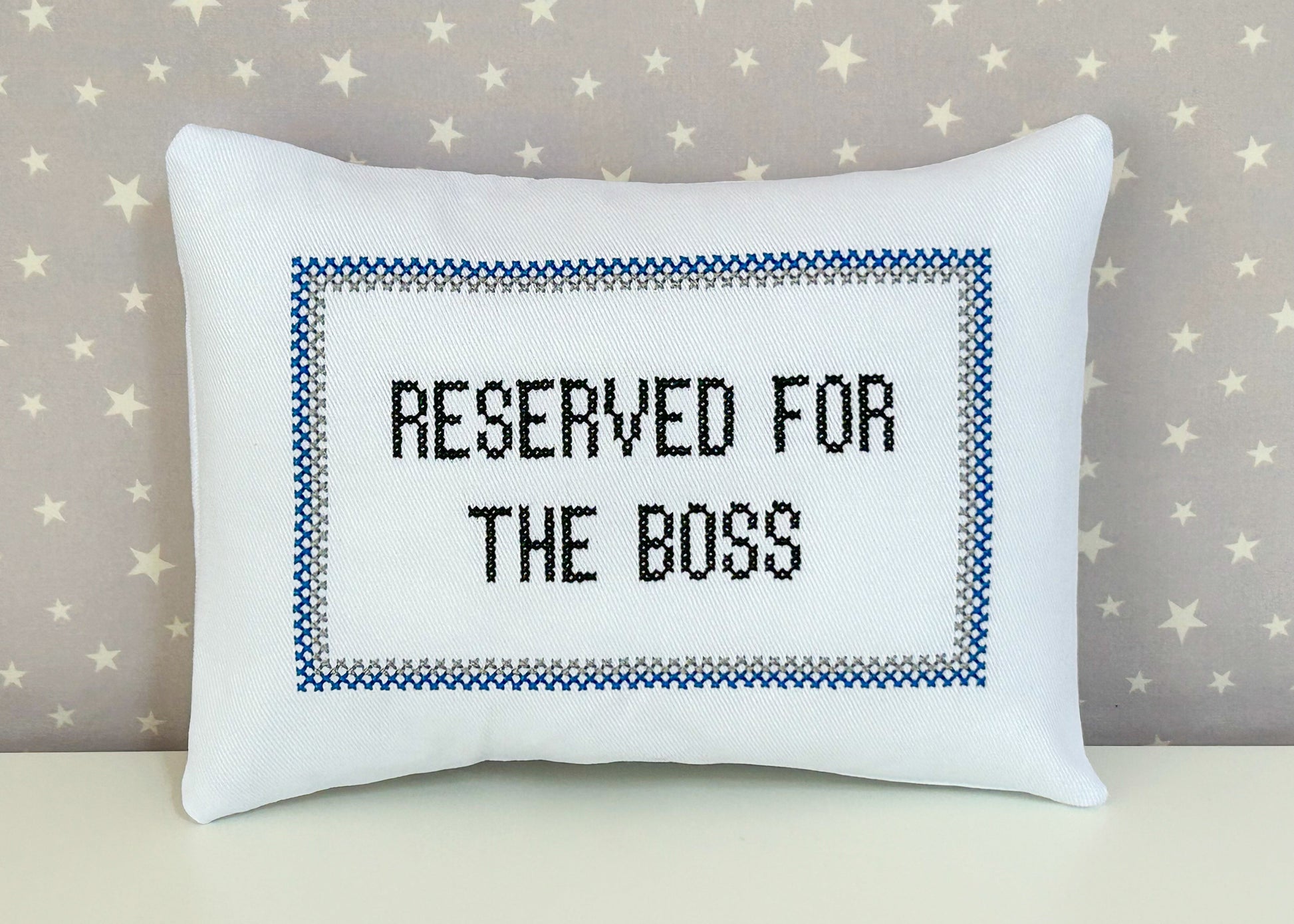 White pillow with 'Reserved for the Boss' text on a star-patterned background