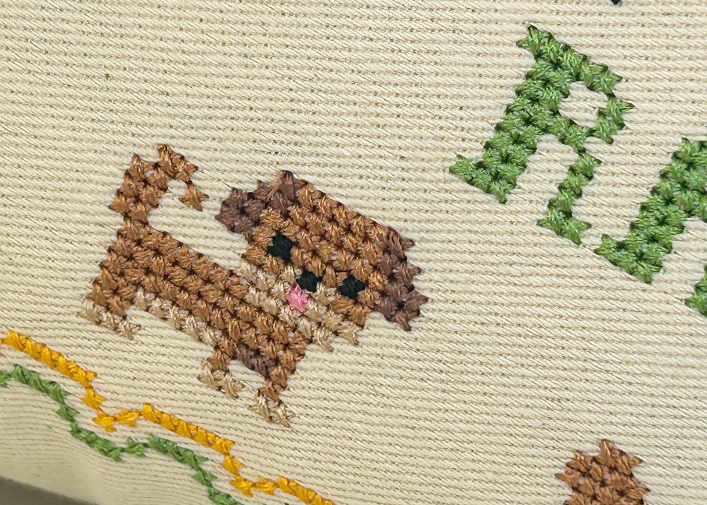 Cross-stitched dog on fabric with greenery