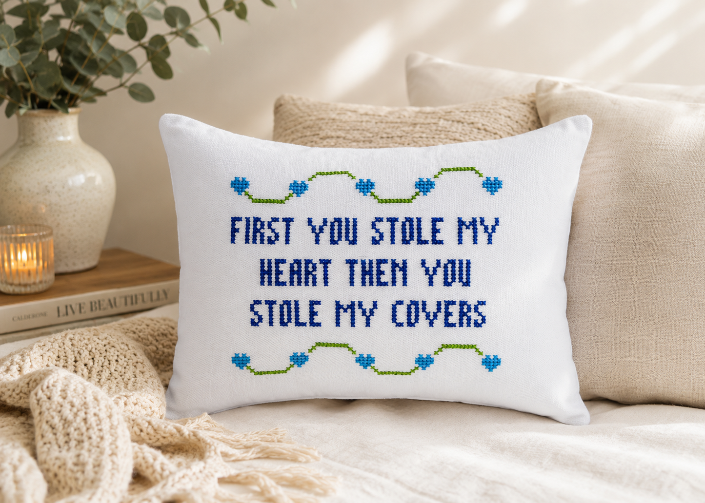 Decorative pillow with cross-stitched text on a couch
