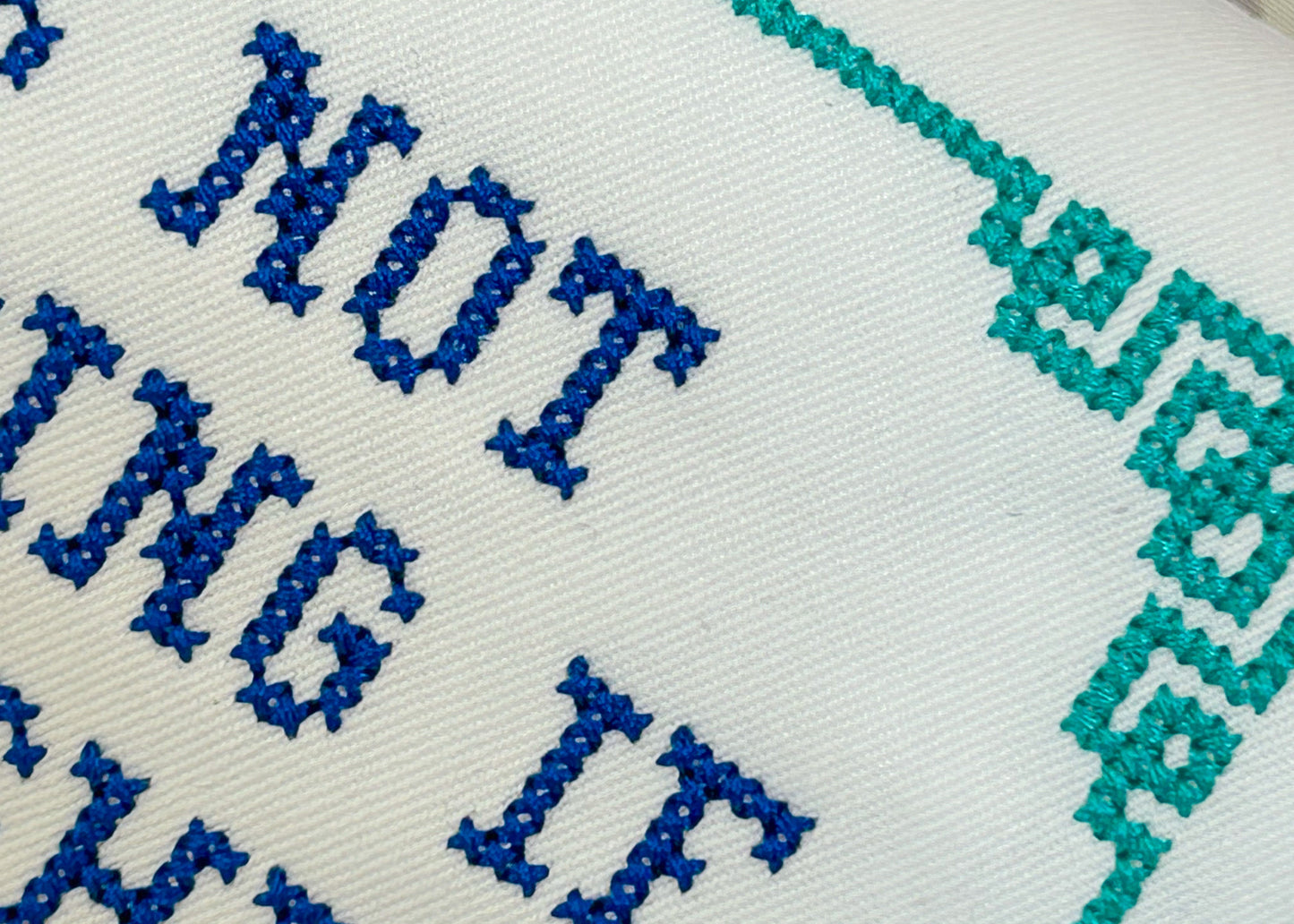 Embroidery with blue and green thread on a white fabric