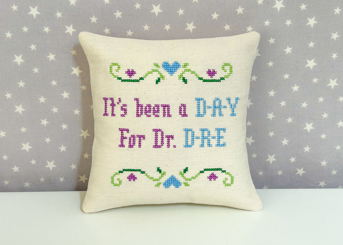 Decorative pillow with cross-stitched text on a star-patterned background