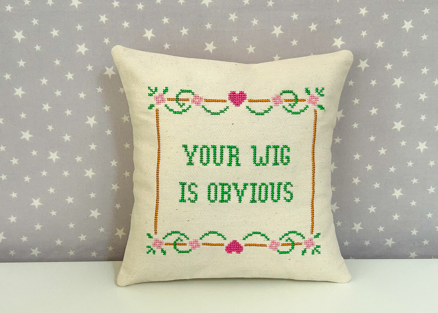 Decorative pillow with cross-stitched text on a star-patterned background