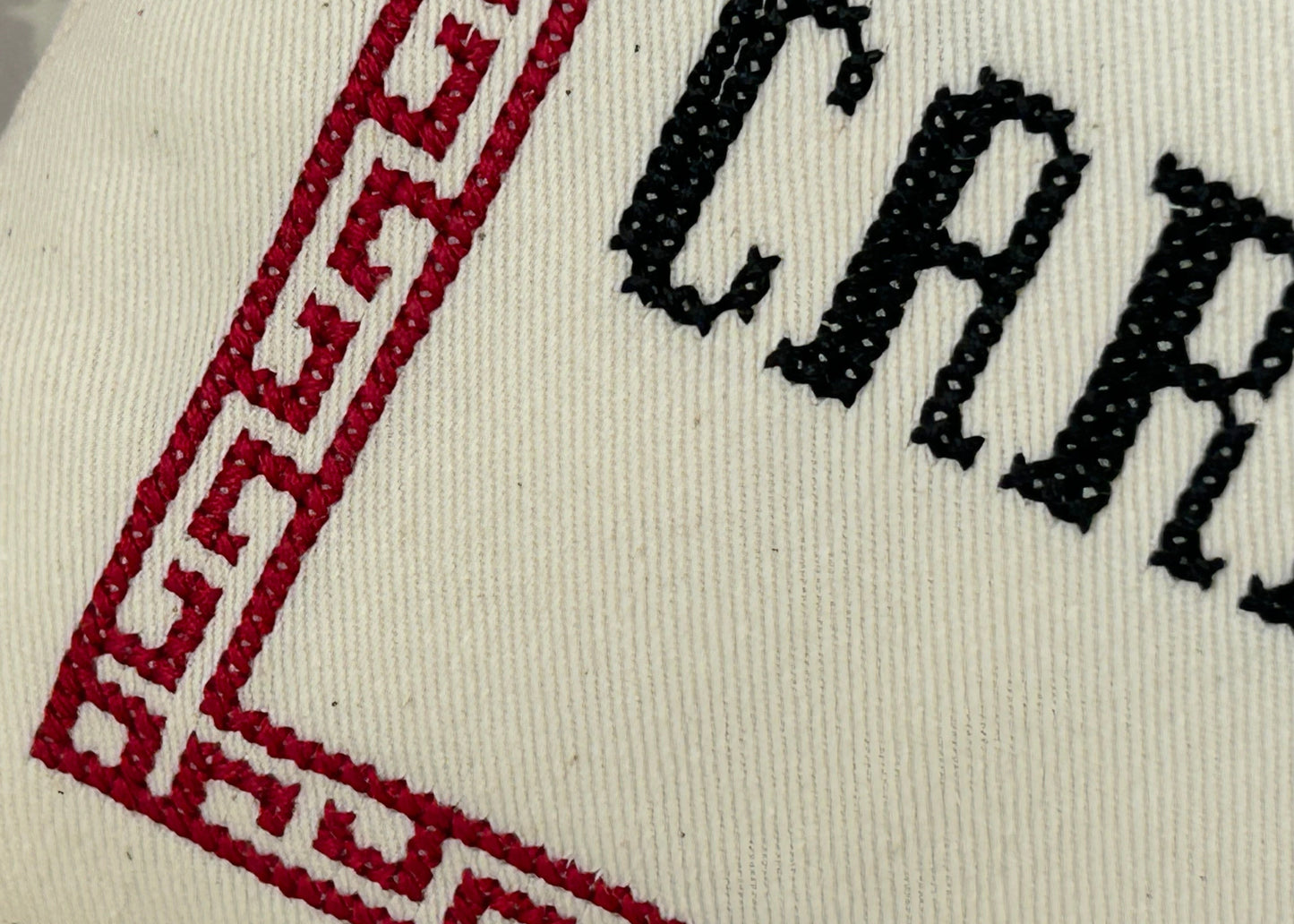 Close-up of a white fabric with red and black embroidery, featuring the brand name 'Carnaby'.