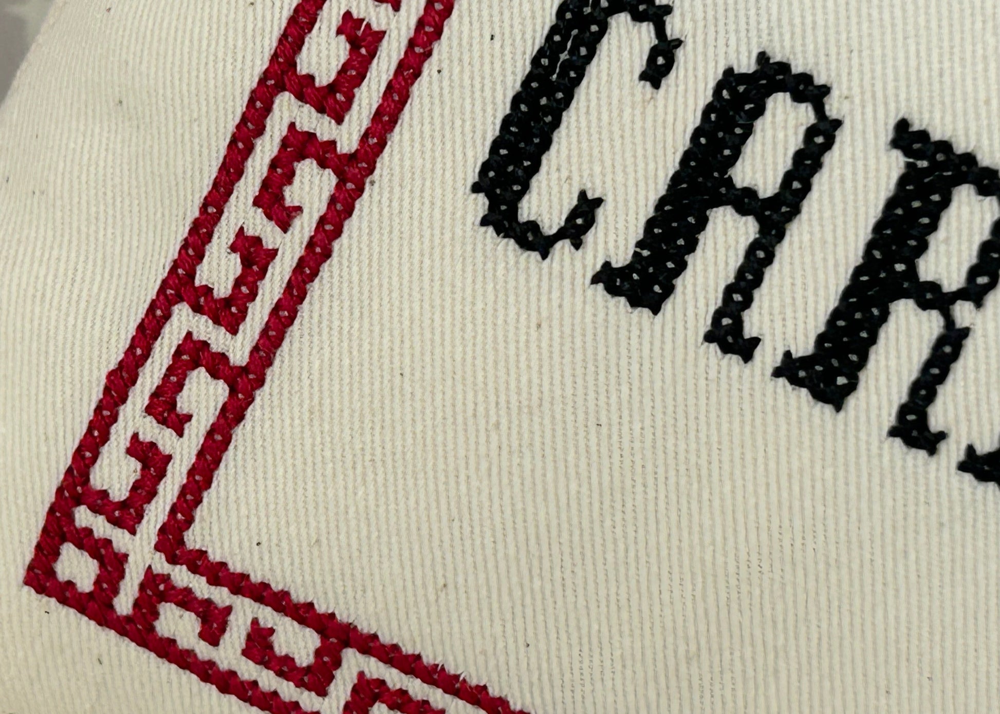Close-up of a white fabric with red and black embroidery, featuring the brand name 'Carnaby'.