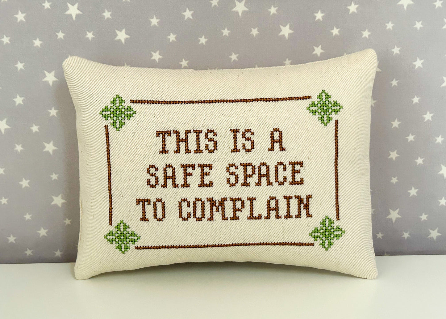 Decorative pillow with cross-stitched text on a star-patterned background