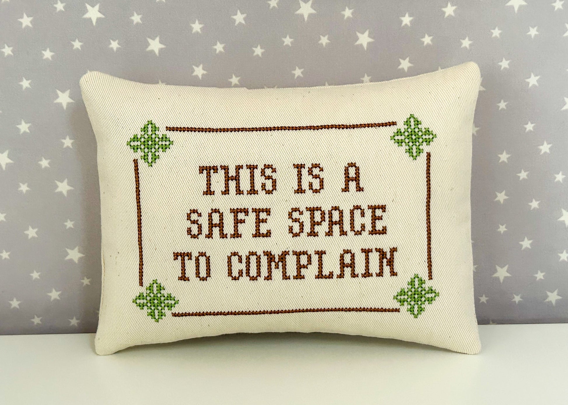 Decorative pillow with cross-stitched text on a star-patterned background