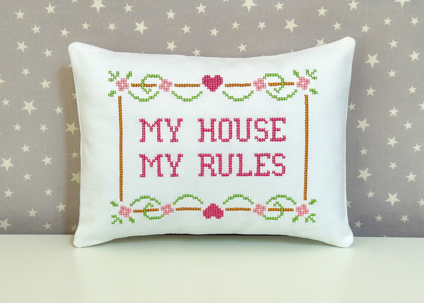 Decorative pillow with cross-stitched text 'My House My Rules' on a star-patterned background