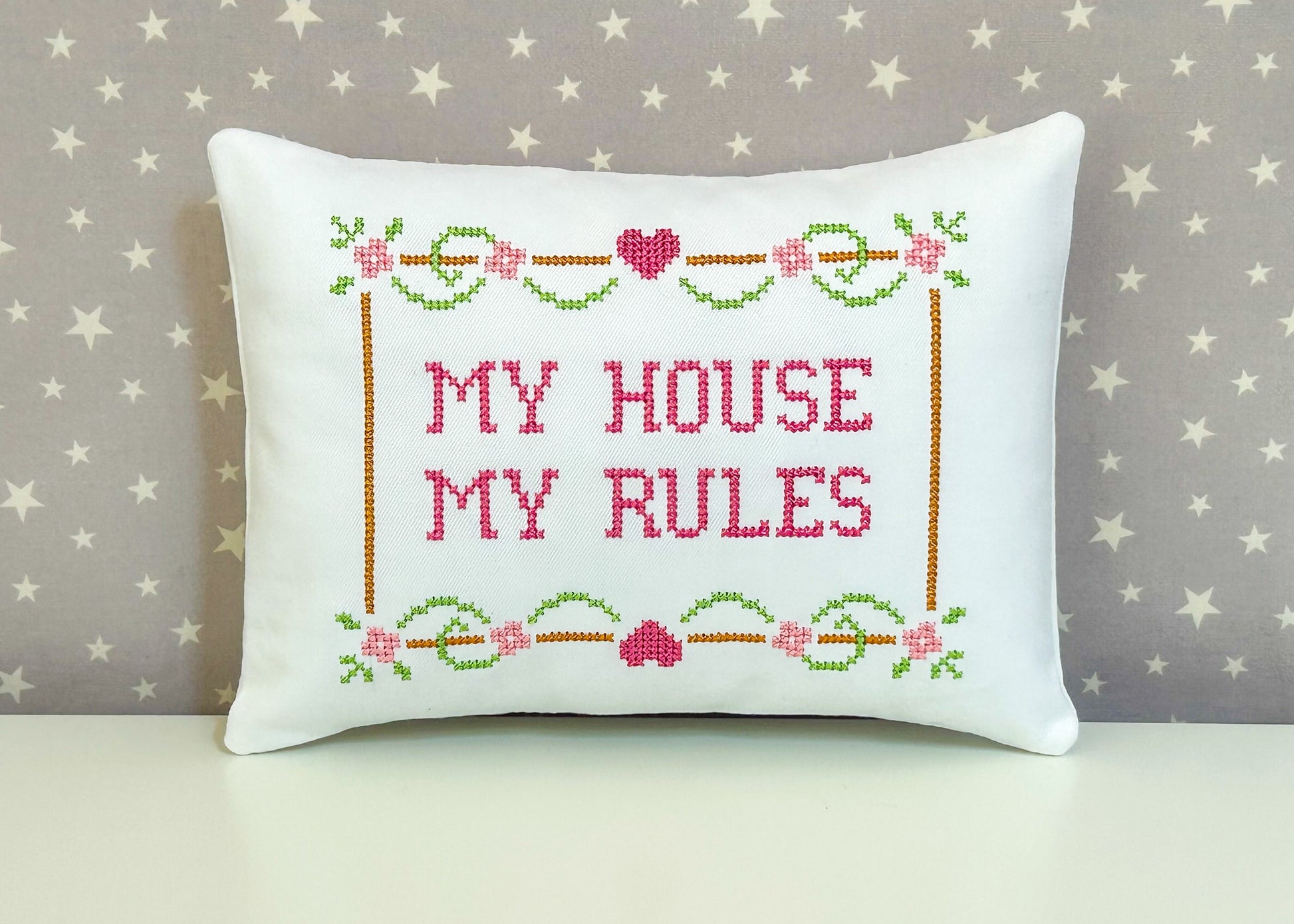 Decorative pillow with cross-stitched text 'My House My Rules' on a star-patterned background