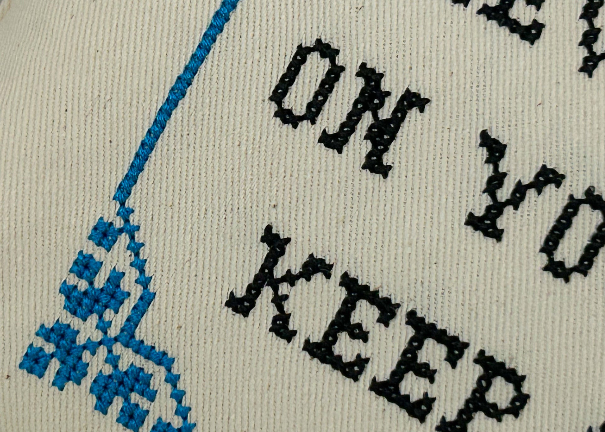 Textured fabric with embroidered text and blue geometric pattern