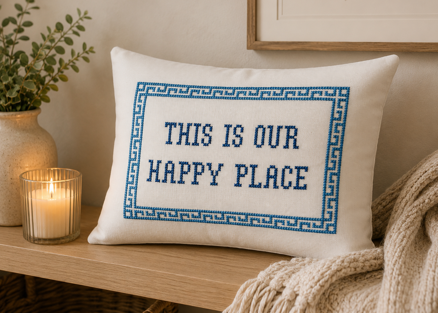 Decorative pillow with 'This is our happy place' text on a wooden surface with candles and plants.