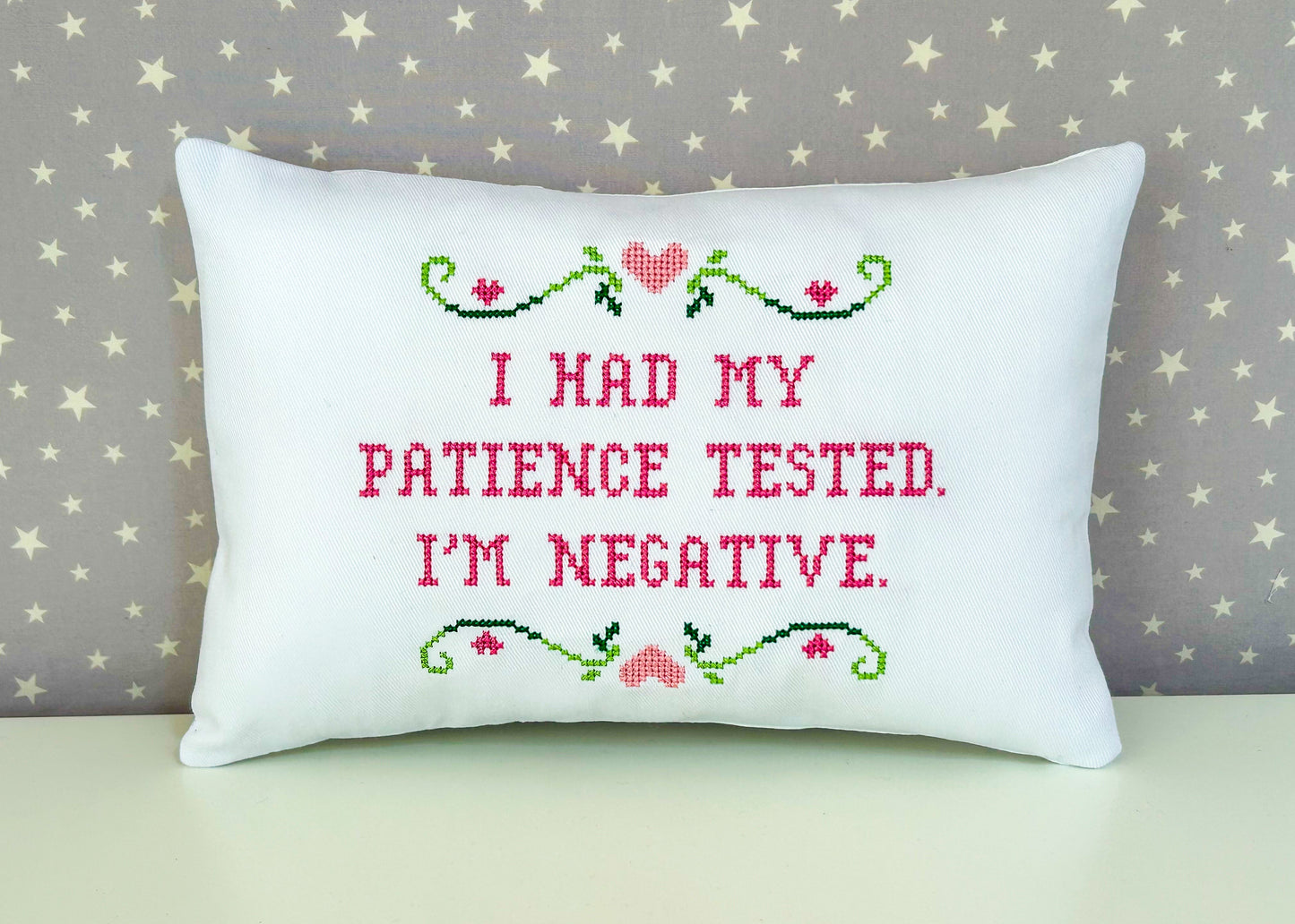 Decorative pillow with cross-stitched text and design on a star-patterned background