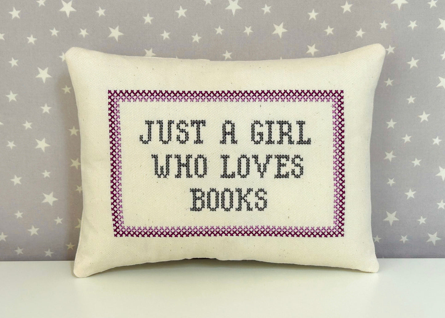 Decorative pillow with 'Just a girl who loves books' text on a star-patterned background