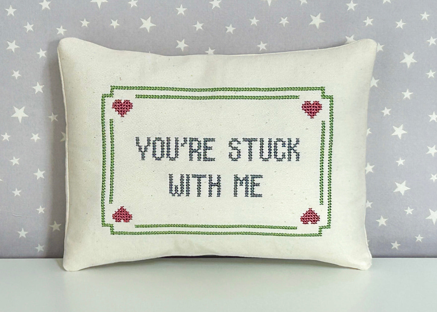 Decorative pillow with embroidered text and hearts on a star-patterned background