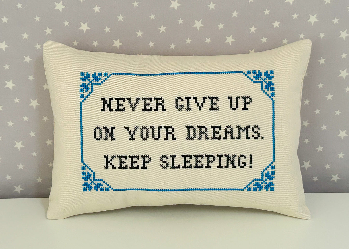 Decorative pillow with embroidered text on a star-patterned background