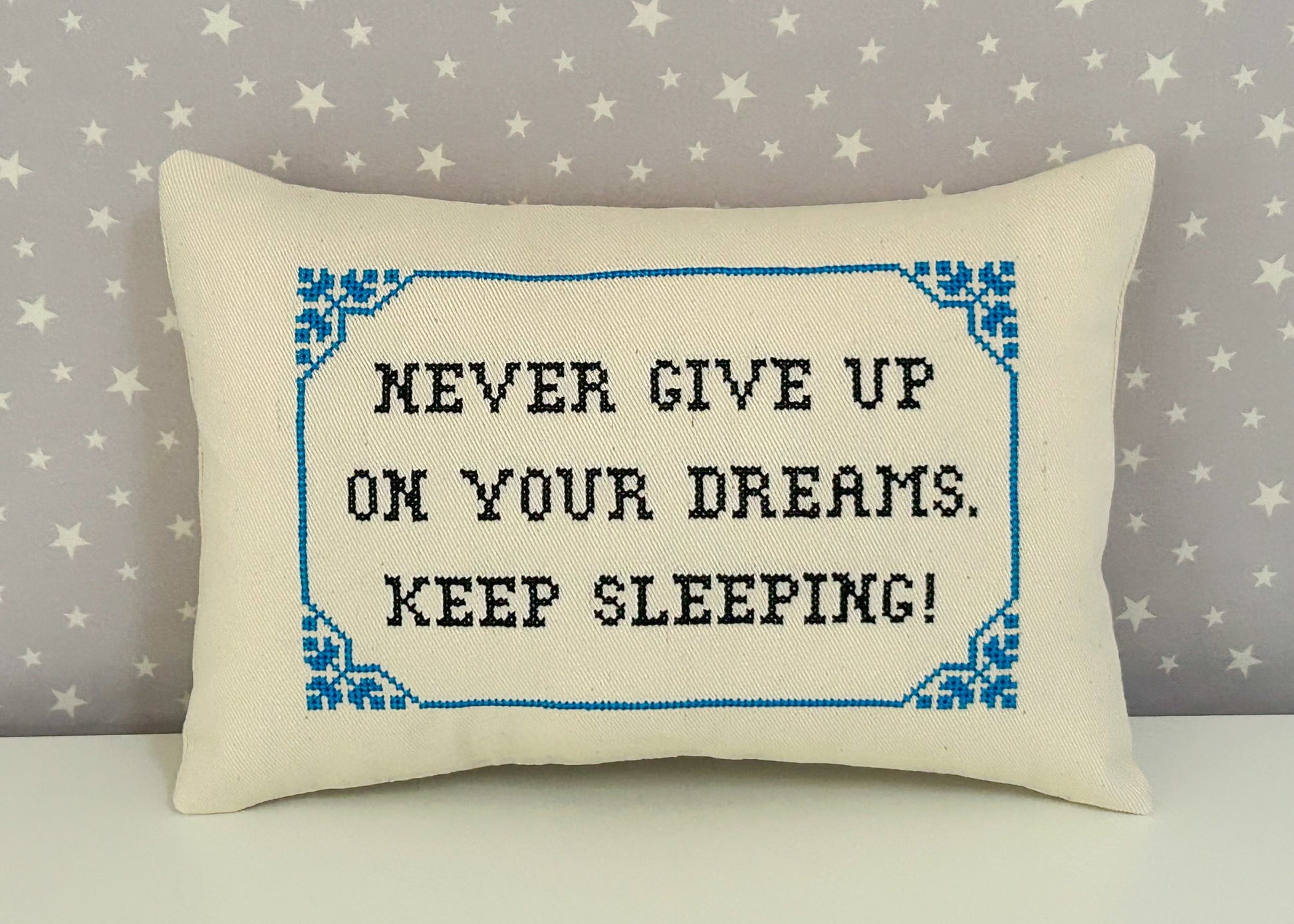 Decorative pillow with embroidered text on a star-patterned background