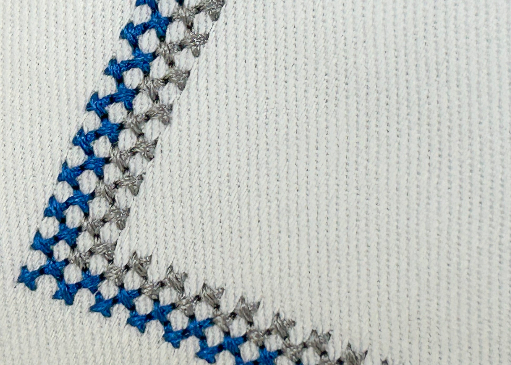 Close-up of a textured fabric with blue, gray, and white pattern on a light gray background