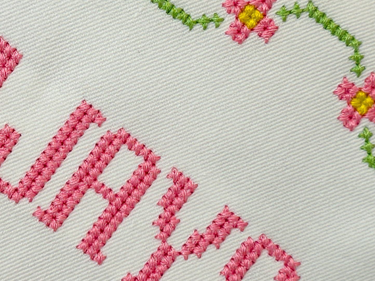 Embroidered text with floral designs on a light background