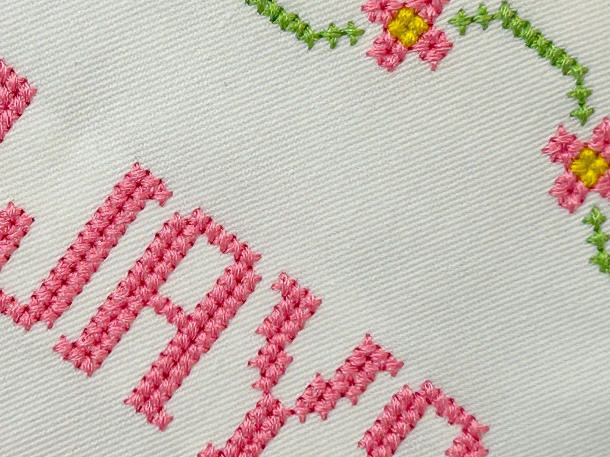 Embroidered text with floral designs on a light background