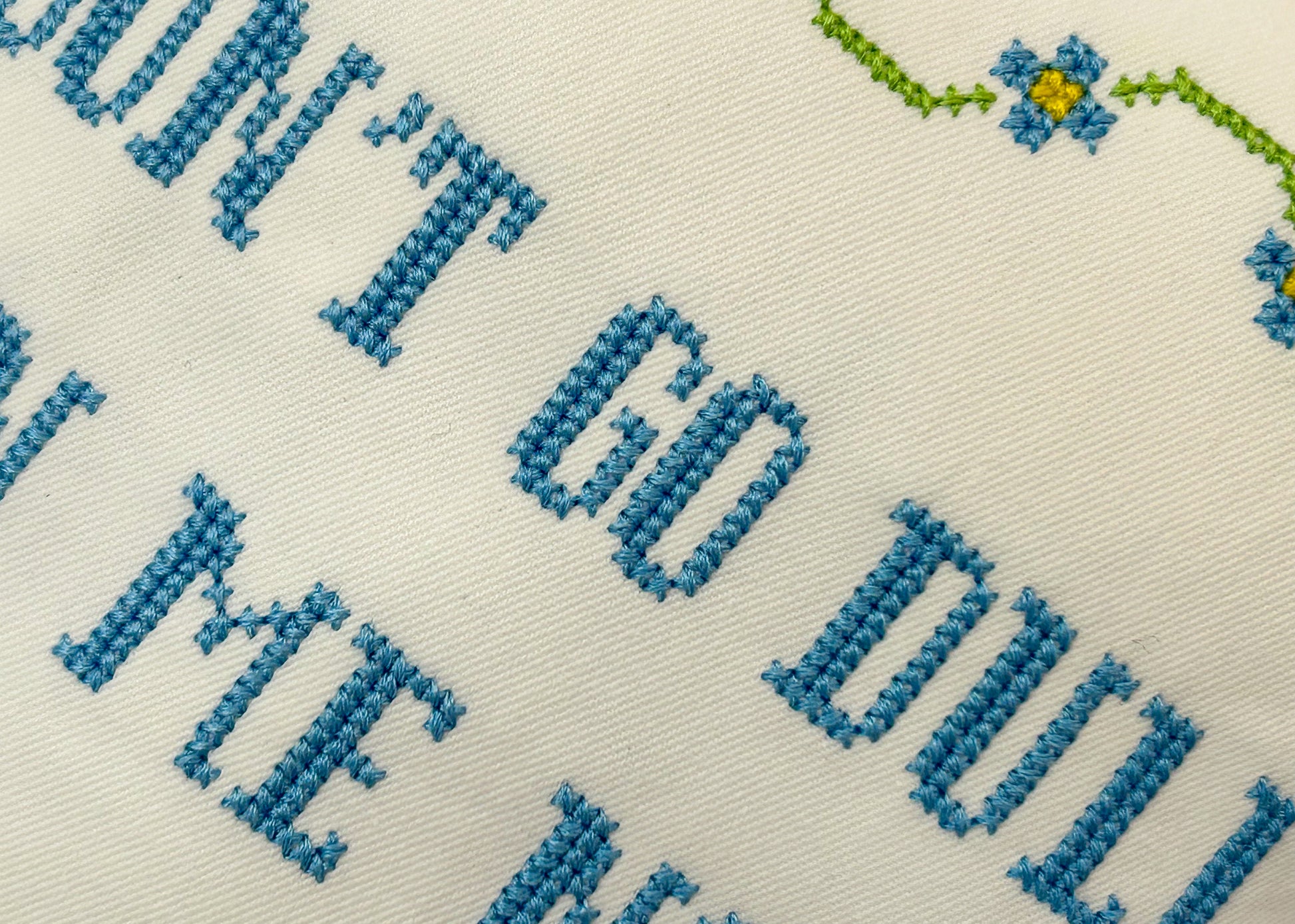 Textile with blue embroidered letters on a beige background