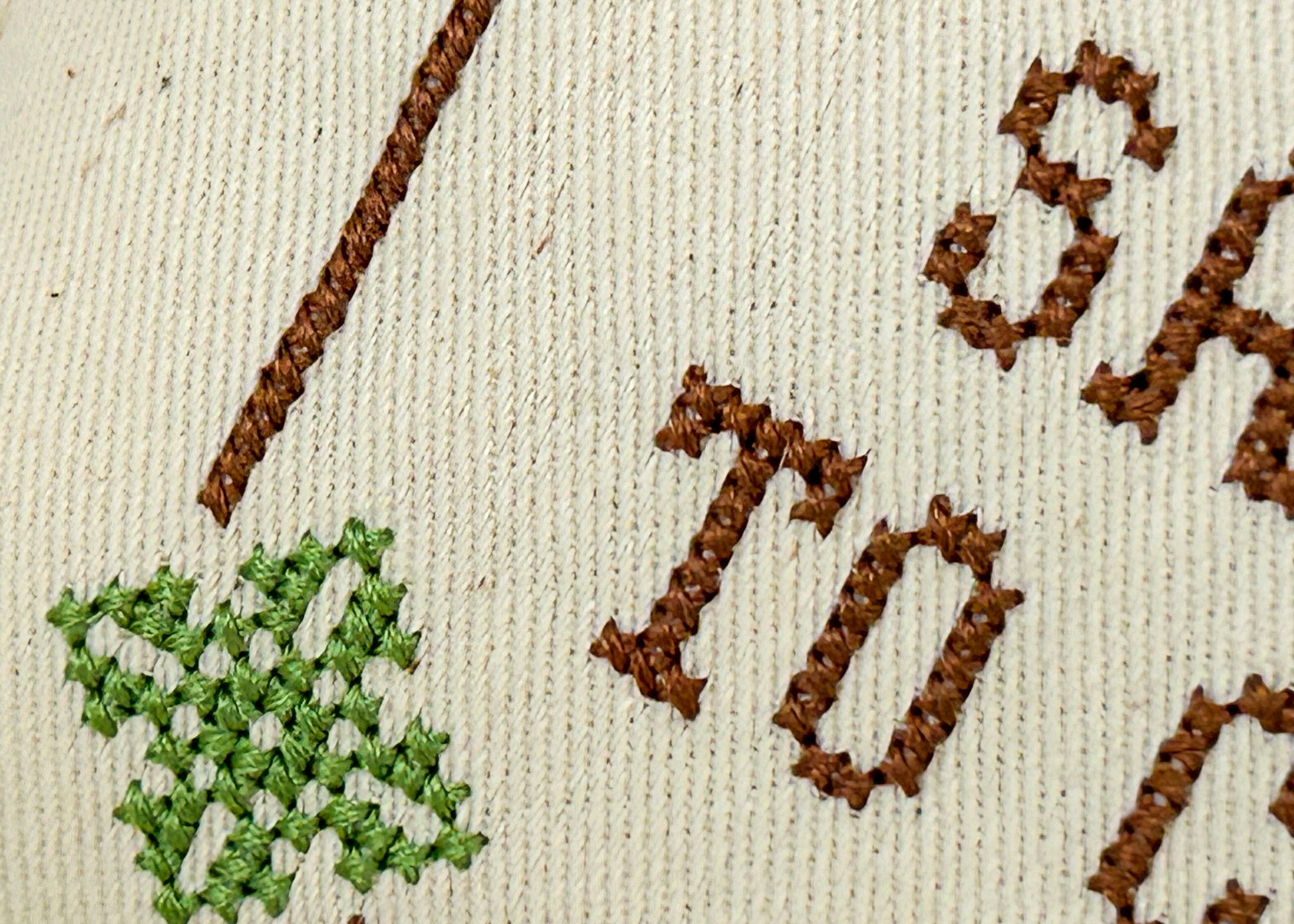 Embroidered text and green leaf design on fabric