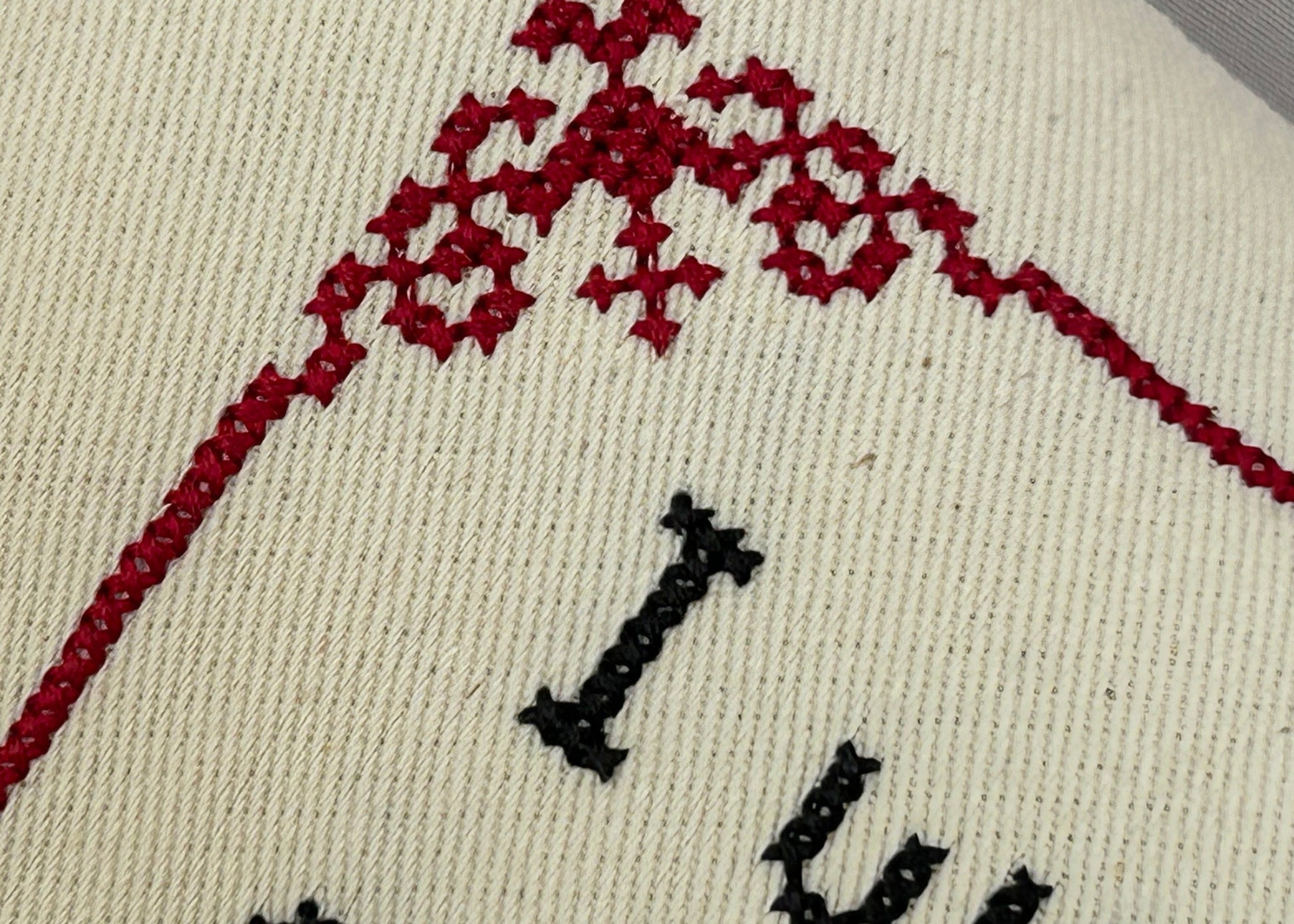 Embroidered design on fabric with red floral pattern and black text.