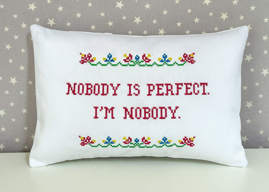 Decorative pillow with cross-stitched text and floral patterns on a star-patterned background