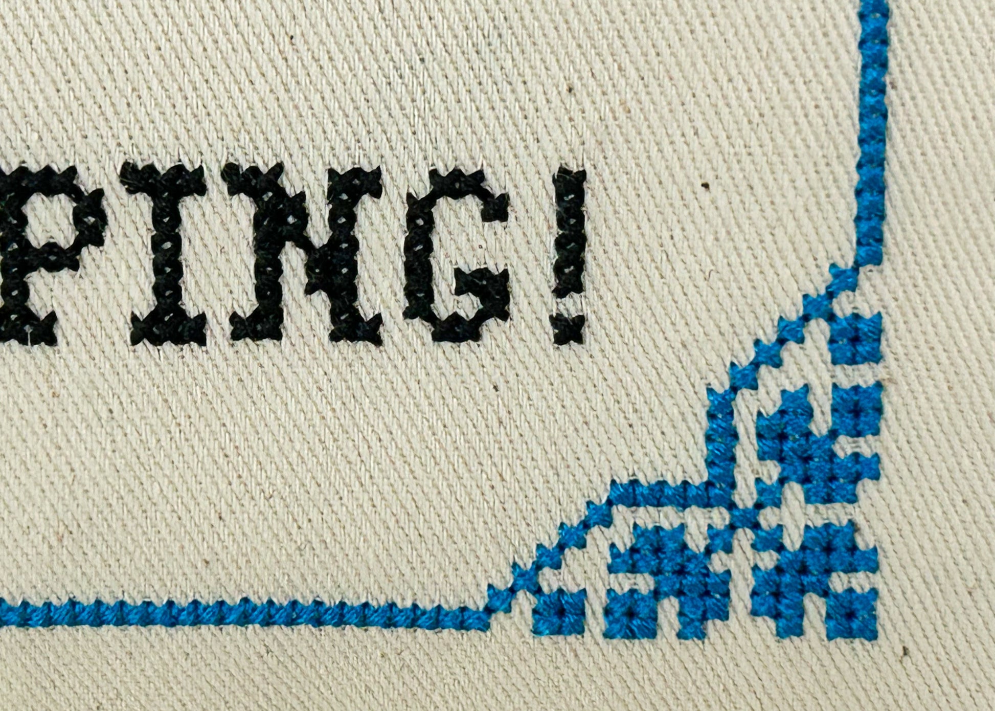 Text 'PING!' in black on a white background with blue stitching