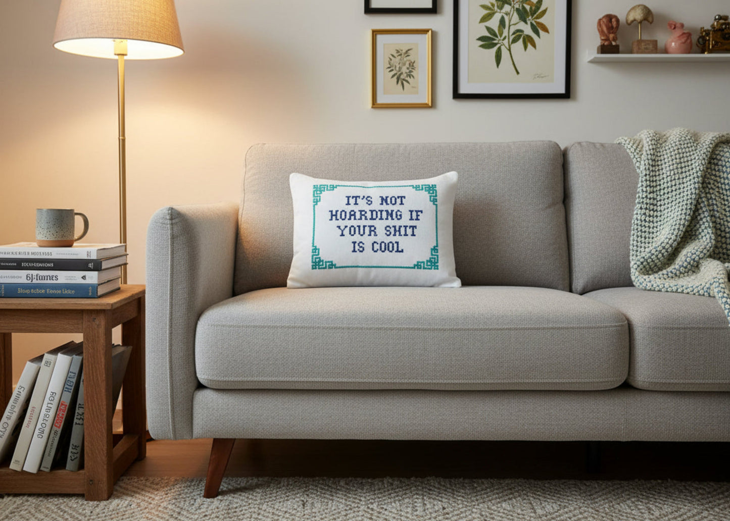 Gray sofa with a decorative pillow and books on a side table in a living room setting.
