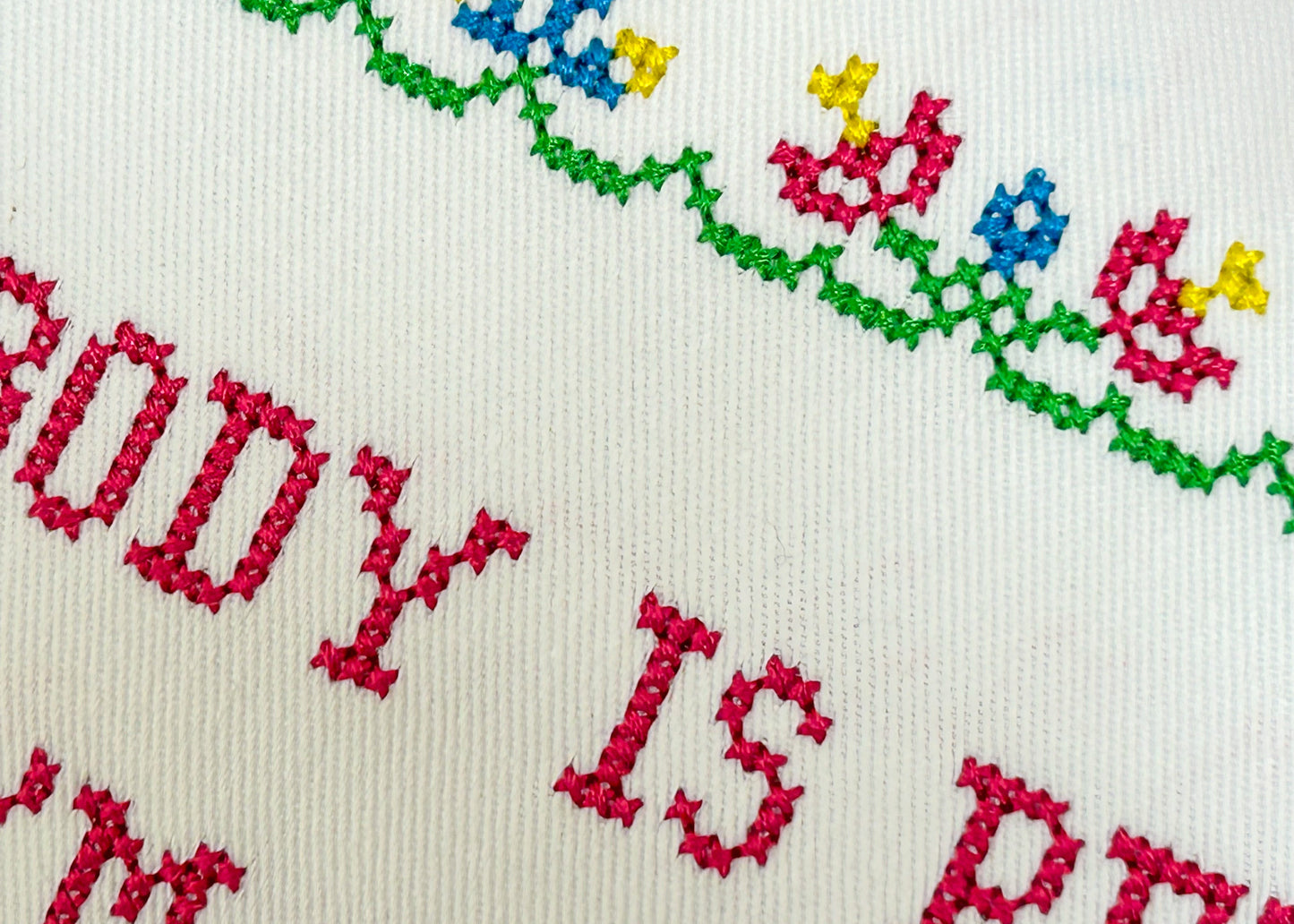 Embroidery with colorful floral pattern and red text on a white background