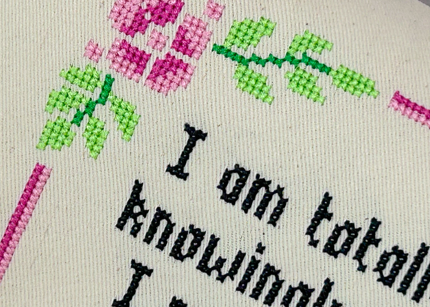 Cross-stitched text with flowers on a fabric background