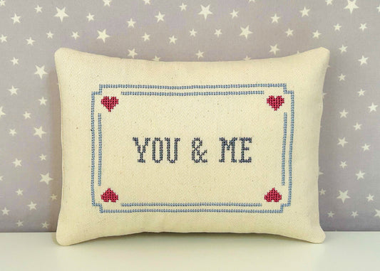 Decorative pillow with 'YOU & ME' text and heart designs on a star-patterned background