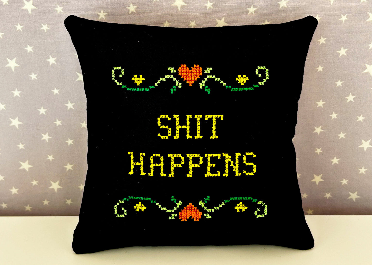 Black pillow with colorful text and patterns on a star-patterned background