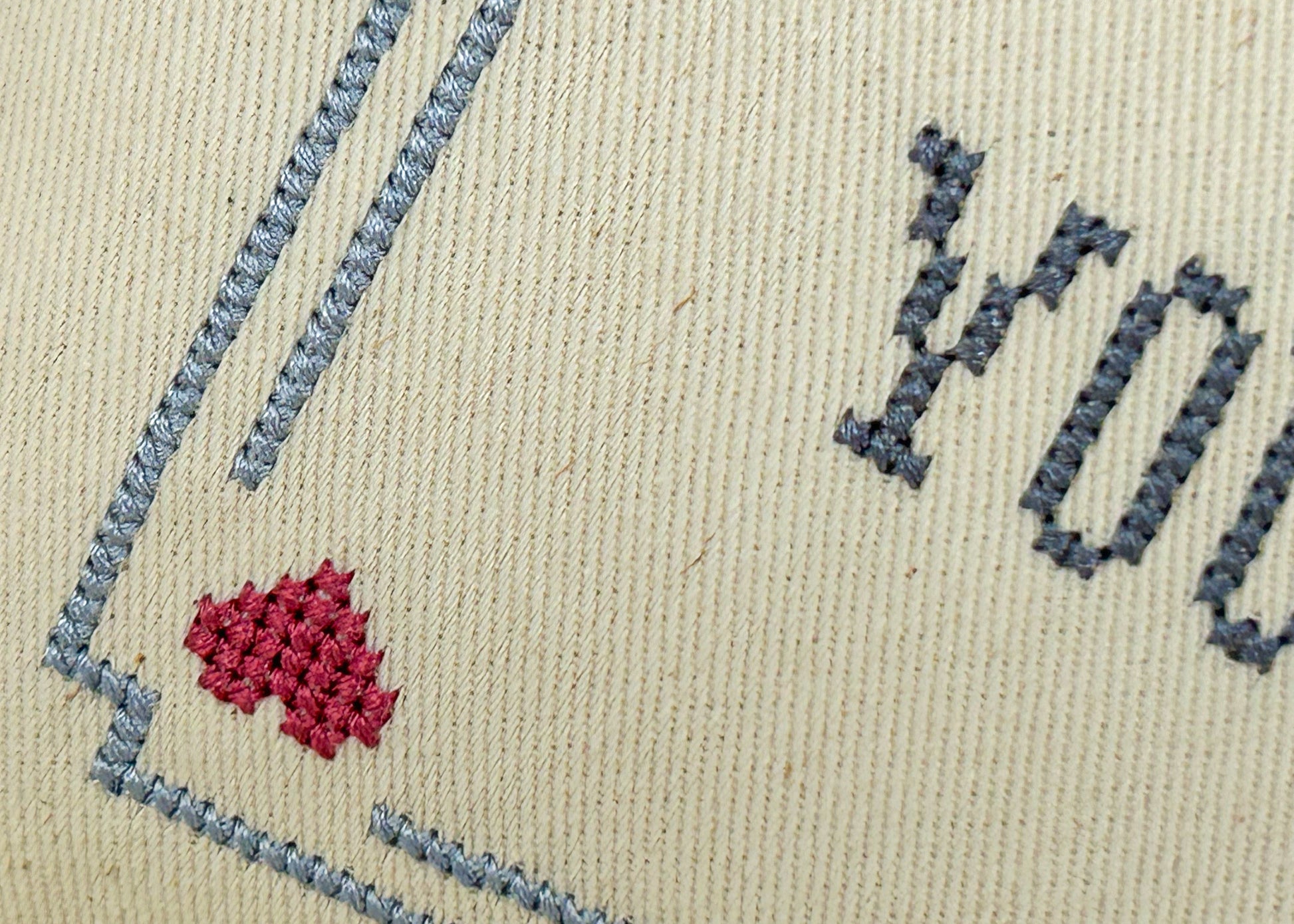 Embroidery with blue and red stitches on beige fabric