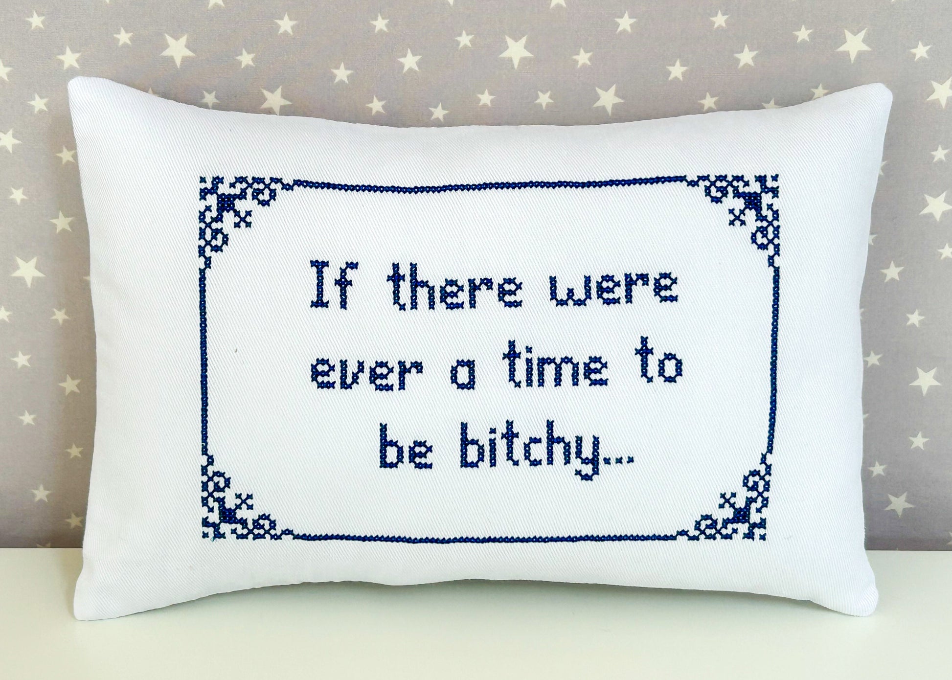 Decorative pillow with cross-stitched text on a star-patterned background